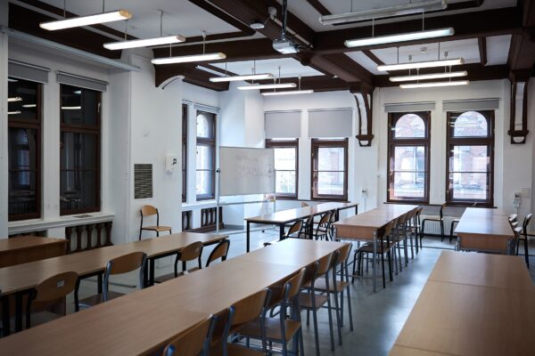 sala wykładowa z ławkami i krzesłami
