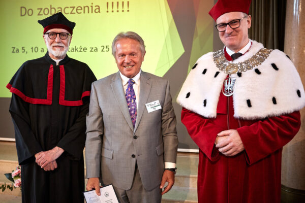 Trzech mężczyzn pozuj do zdjęcia, dwóch z nich ubranych jest w togi akademickie