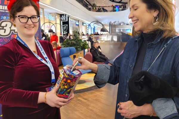 Dwie kobiety stoją w centrum handlowym. Jedna z nich trzyma puszkę WOŚP